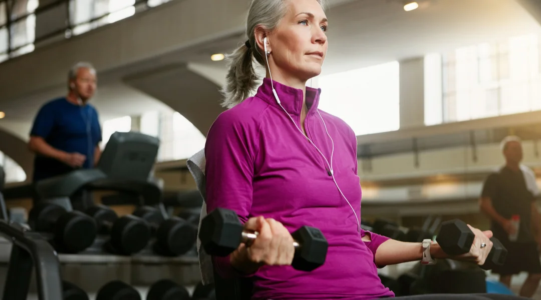 Une femme âgée fait des exercices dans une salle de sport, promouvant un environnement sans jugement.