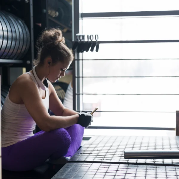 Une femme assise sur un tapis devant une fenêtre, dans un espace de gym sans jugement.